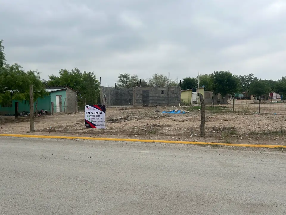 El terreno visto desde la calle pavimentada, con el letrero de venta